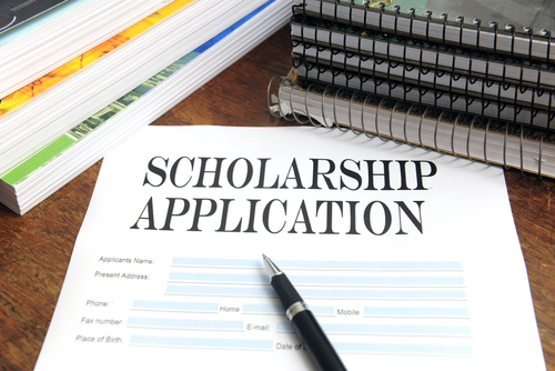 paper application for a scholarship lying on a table, with a pen on top